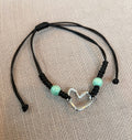Lure Bracelet featuring a silver heart charm and aqua beads on a black cord, perfect for stylish accessories.