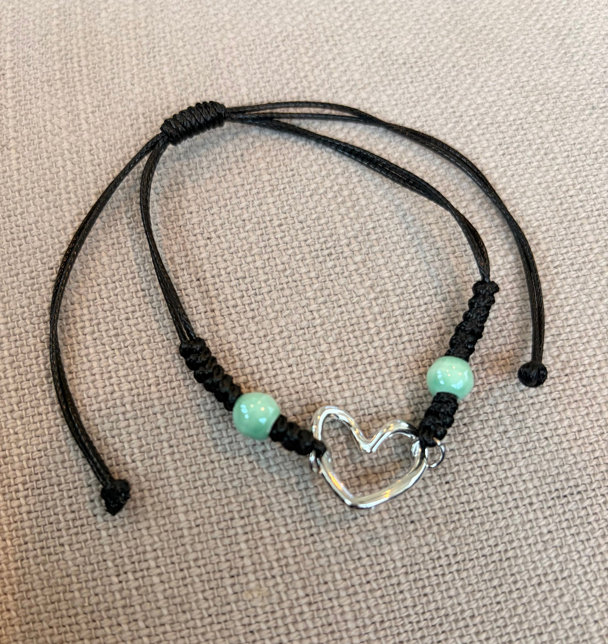 Lure Bracelet featuring a silver heart charm and aqua beads on a black cord, perfect for stylish accessories.
